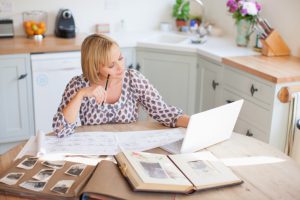 Smiling woman at table with old photographs and genealogical tree